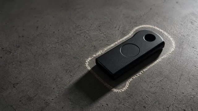 A matte black hardware security key resting on weathered concrete, encircled by a hand-drawn chalk perimeter, lit by a single cold directional light from the upper right.