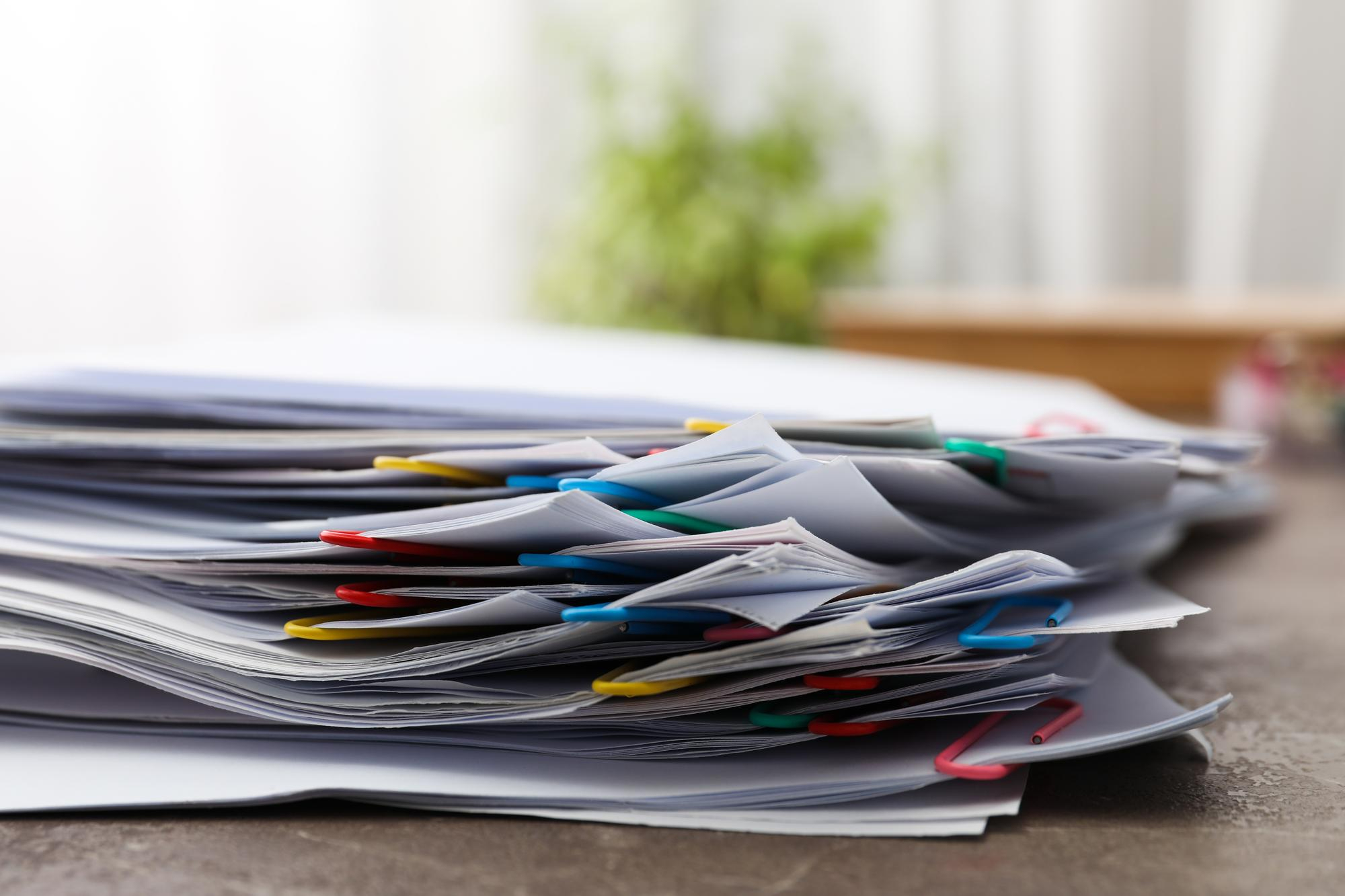 Stack of paper documents with colorful paperclips on a desk