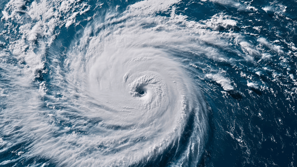 High-resolution satellite view of a powerful hurricane over deep blue ocean waters, with a clear eye and tightly wound spiral cloud bands.